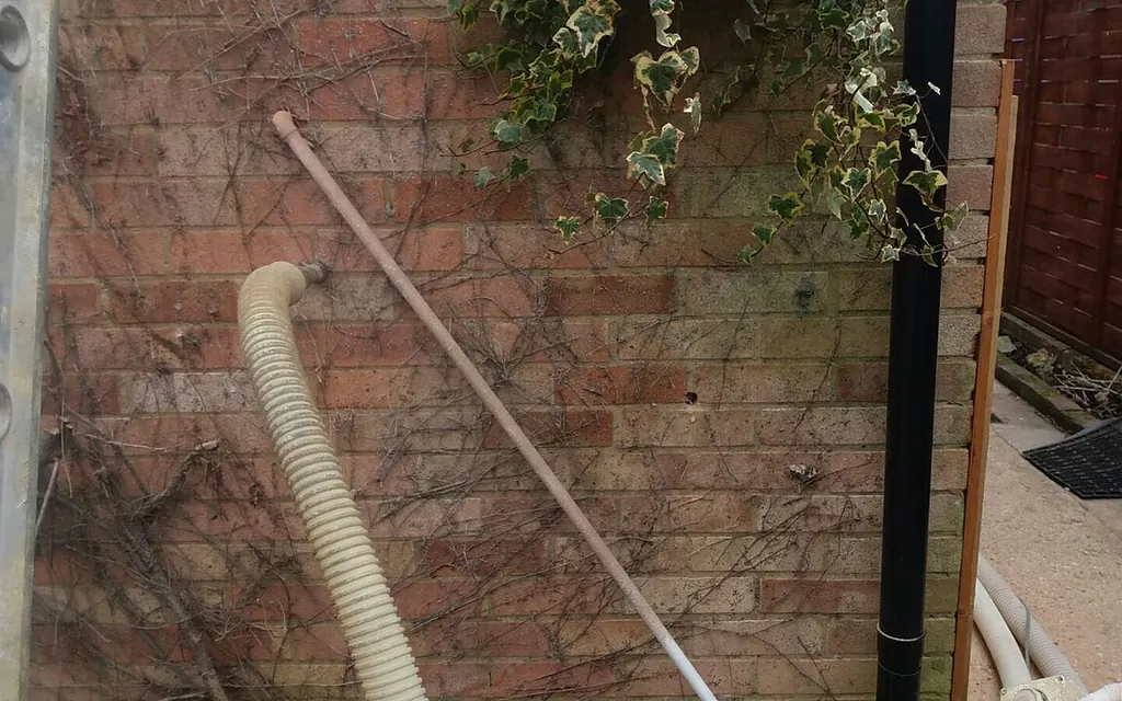 Installer blowing insulation into a cavity wall through drilled holes